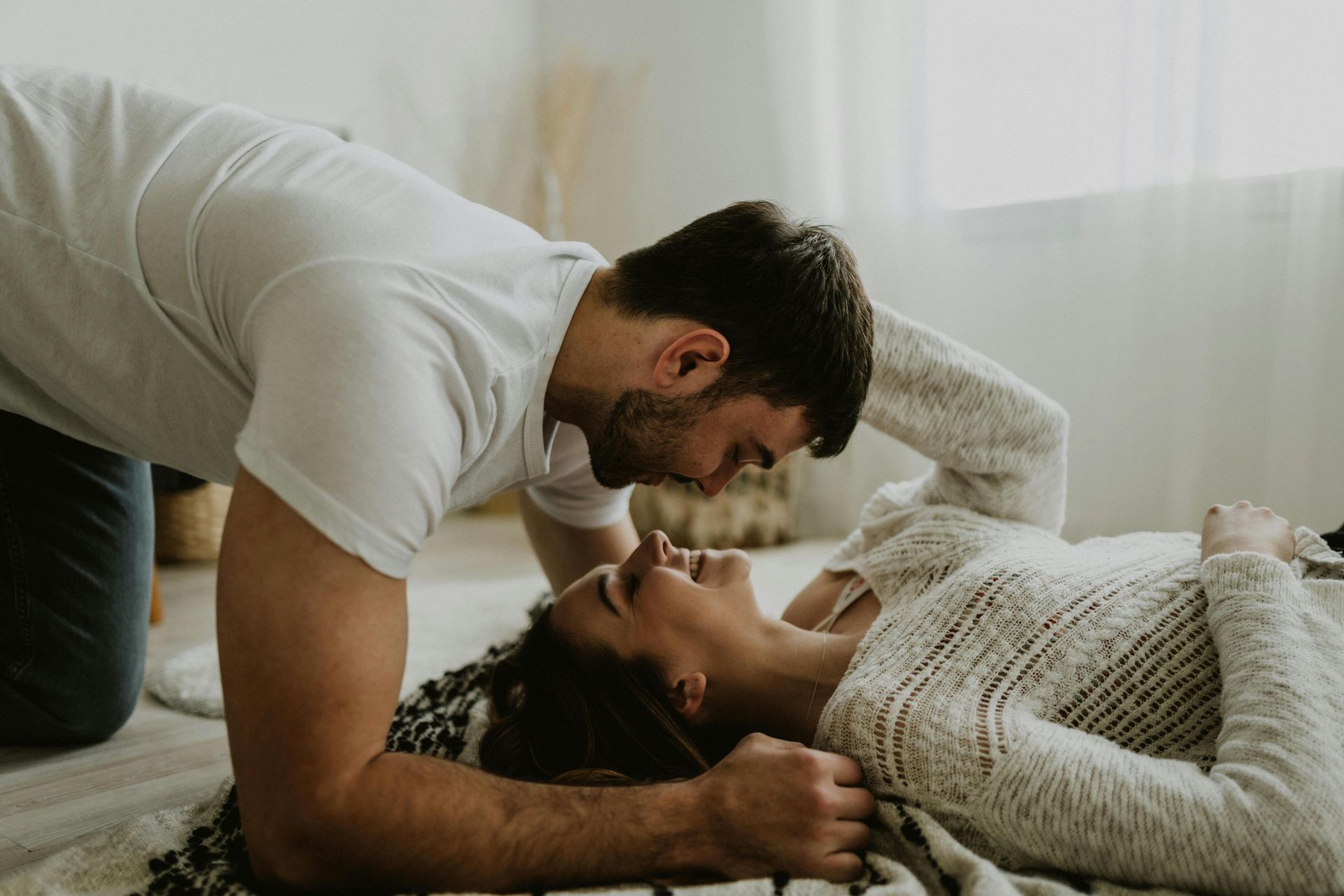 Young couple sharing a joyful and intimate moment together on the floor indoors.