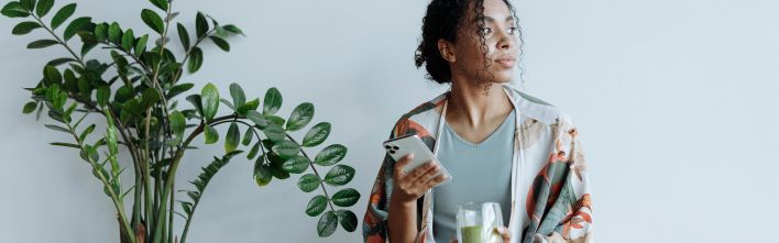 A thoughtful woman enjoying tranquil indoor space with a plant and drink.